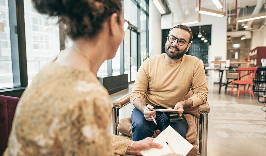 two people talking and taking notes
