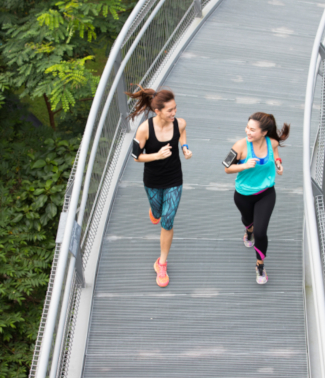  two ladies running on a bridge in a park