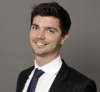 a man wearing a suit and tie smiling at the camera