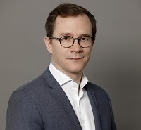 a man wearing a suit and tie smiling and looking at the camera