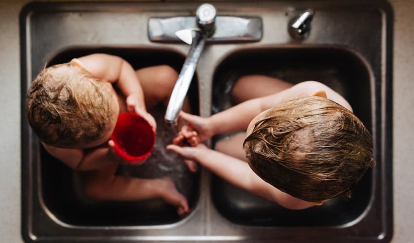 two babies having a bath in the sink