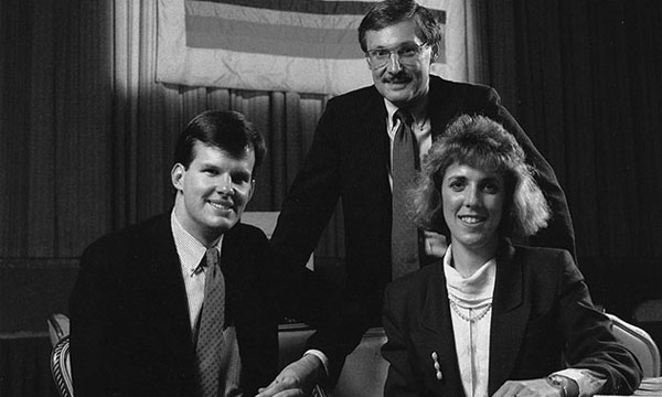 a group of people standing next to a man in a suit and tie