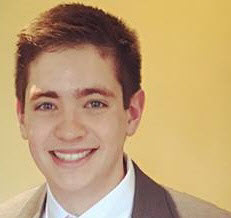 a man wearing a suit and tie smiling at the camera