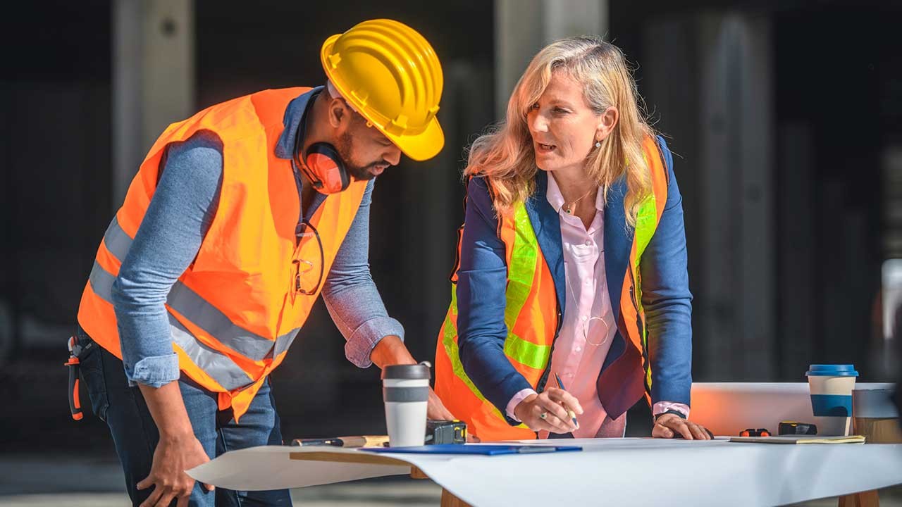 coordinateur de chantier et contremaître debout travaillant sur une table de planification