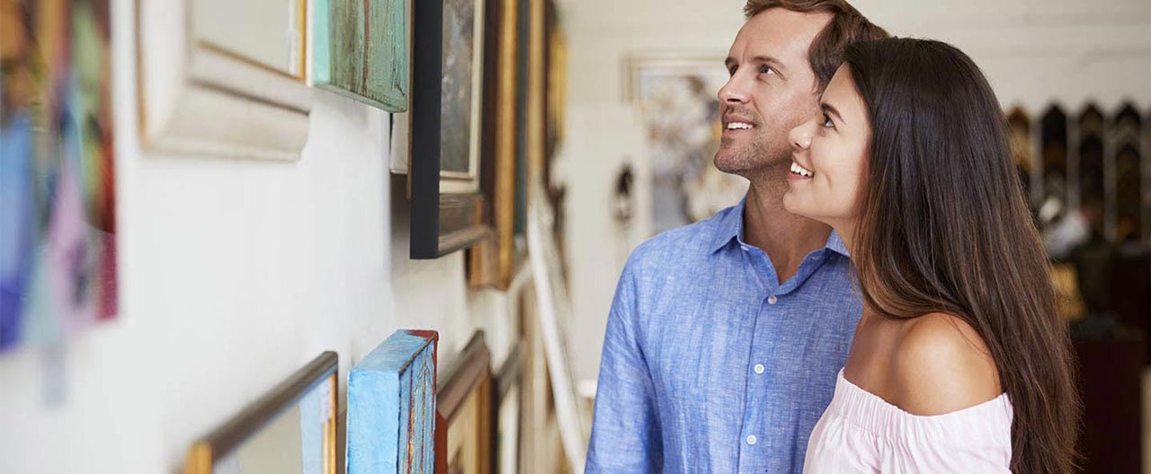 couple looking at paintings in art gallery