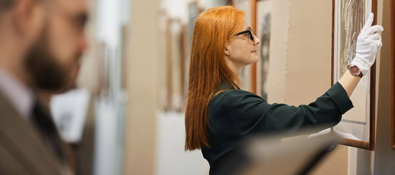 woman hanging painting at gallery