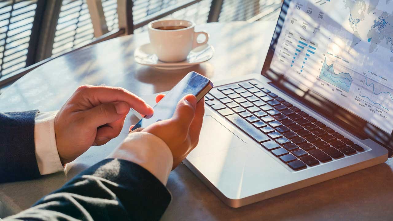 man using a smartphone and laptop